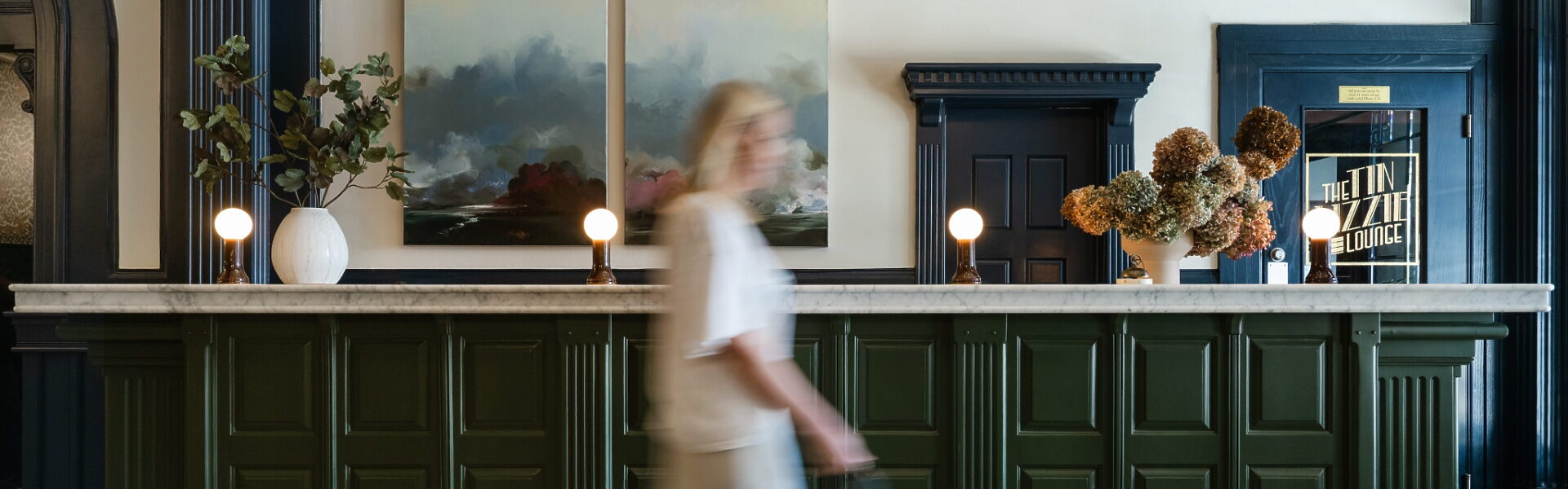 Person walking past the front desk in the lobby at The MarQueen Hotel in Seattle’s Queen Anne neighborhood.